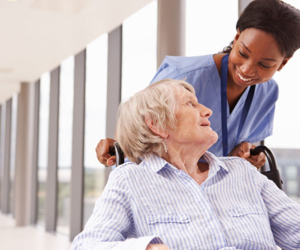 Nurse pushing a woman in wheelchair.